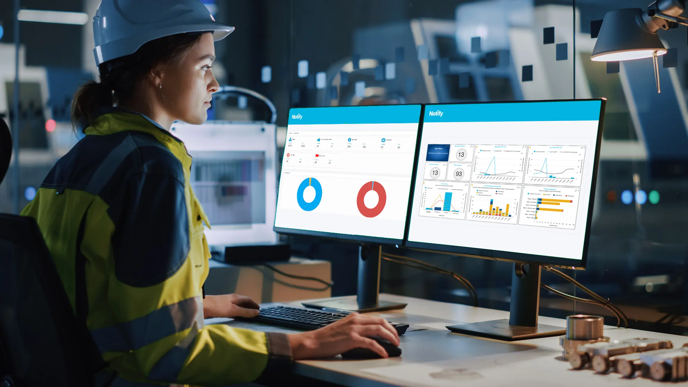 A woman in safety gear looks at a health and safety dashboard on her office computer.